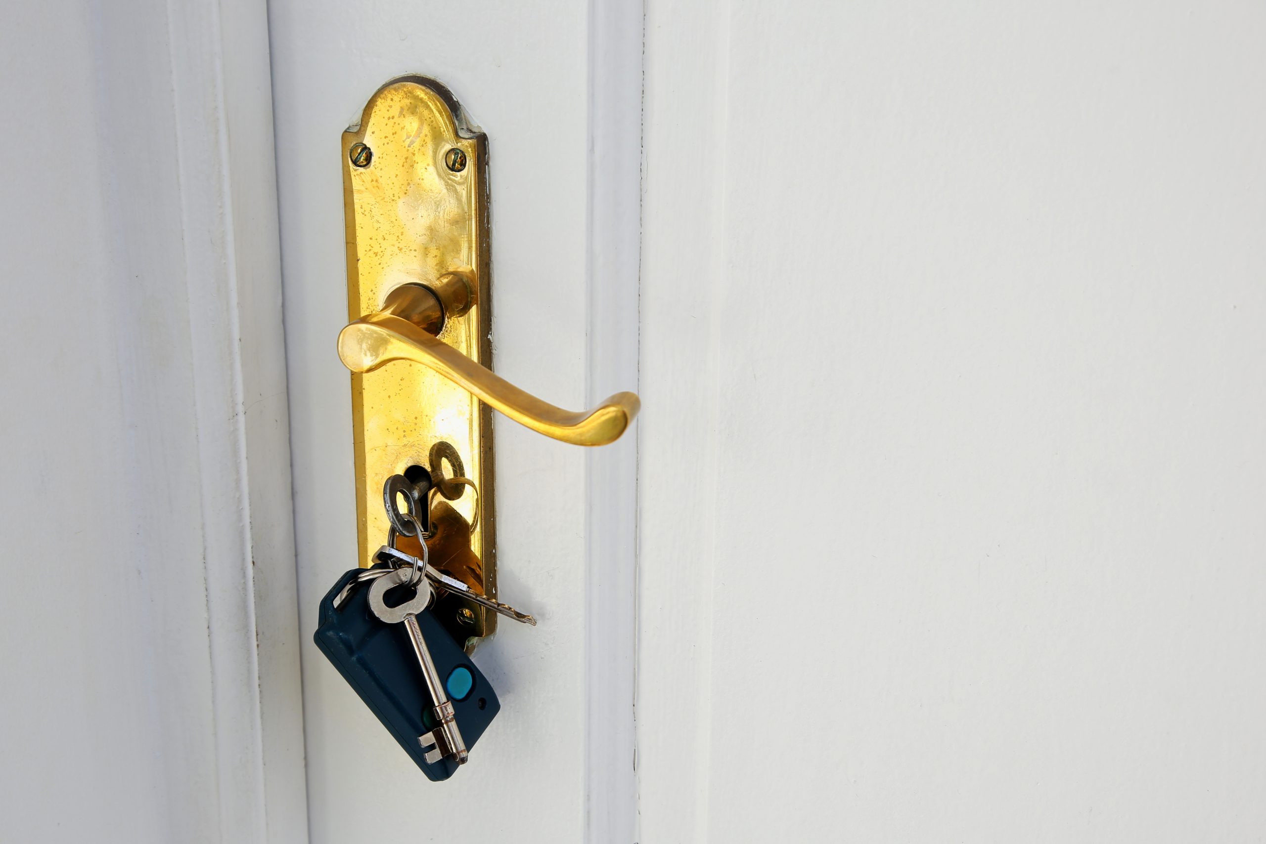 Golden doorknob with keys on a white door